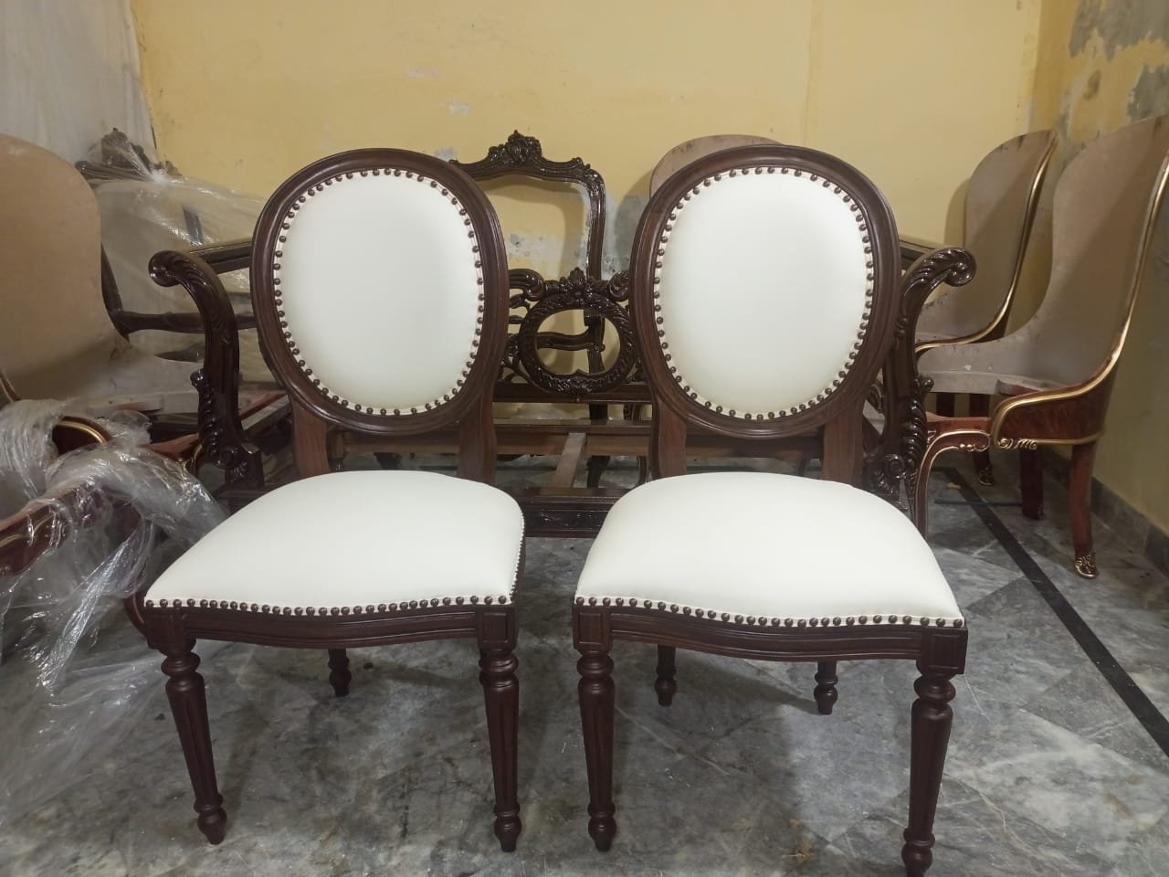 A pair of carved chairs with cream leather upholstery